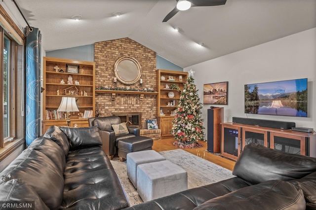 living room featuring a textured ceiling, vaulted ceiling, ceiling fan, wood-type flooring, and a fireplace