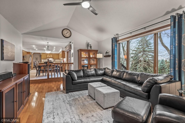 living room with light hardwood / wood-style floors, vaulted ceiling, and ceiling fan