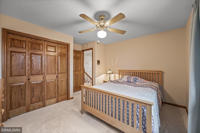 carpeted bedroom with ceiling fan, a textured ceiling, and a closet