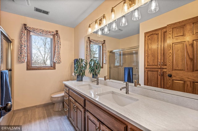 bathroom with vanity, a shower with shower door, and toilet