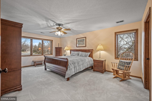 bedroom featuring ceiling fan, light carpet, and a textured ceiling