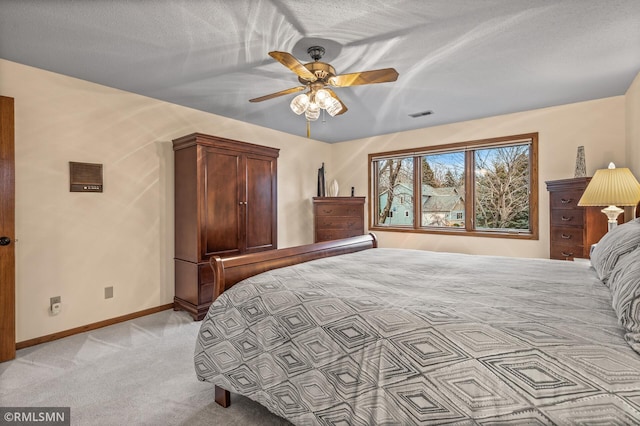 bedroom with ceiling fan, light colored carpet, and a textured ceiling