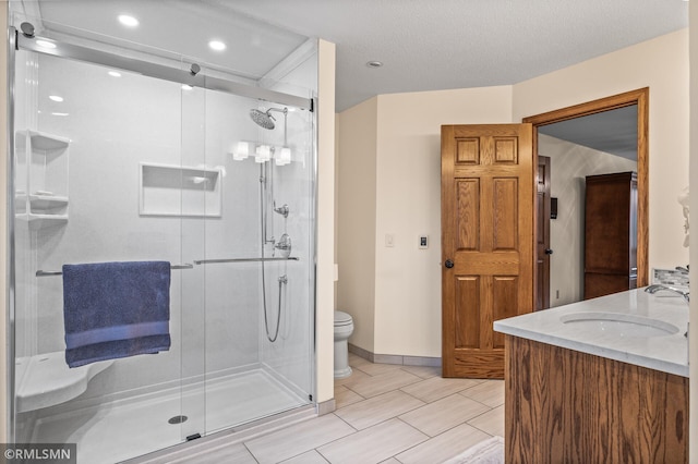 bathroom with vanity, toilet, a shower with door, and a textured ceiling