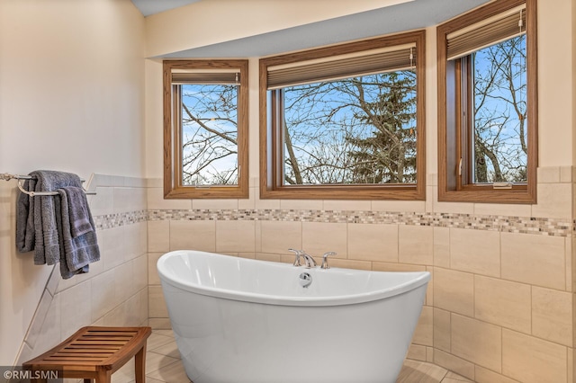 bathroom with tile patterned floors, a bath, and tile walls