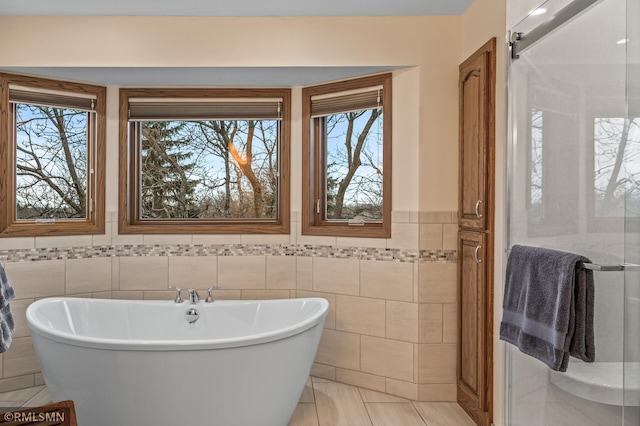 bathroom with a bathing tub, tile patterned flooring, and tile walls