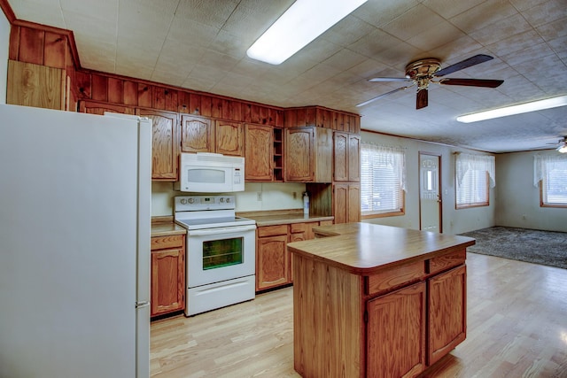 kitchen featuring ceiling fan, a kitchen island, white appliances, and light hardwood / wood-style flooring