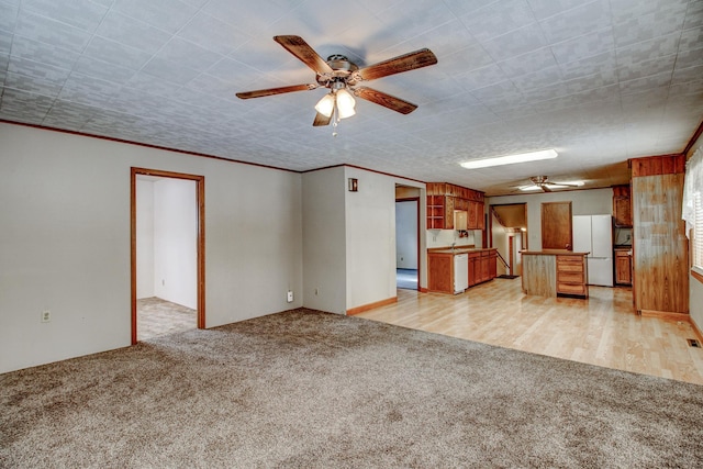 unfurnished living room with light carpet, light wood-type flooring, crown molding, and a ceiling fan