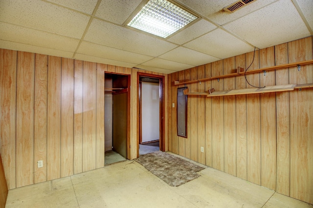 unfurnished bedroom with a closet, visible vents, a paneled ceiling, and wooden walls