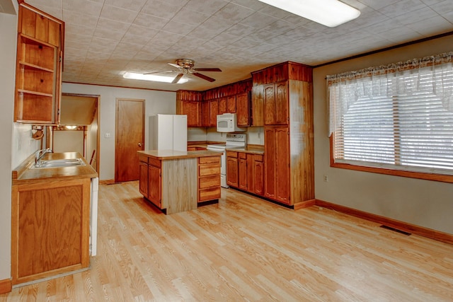 kitchen featuring visible vents, baseboards, light wood-type flooring, white appliances, and a sink