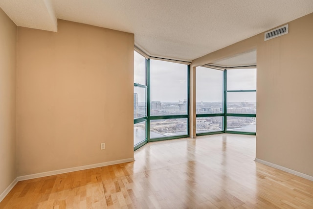 unfurnished room featuring a wall of windows, plenty of natural light, and a textured ceiling