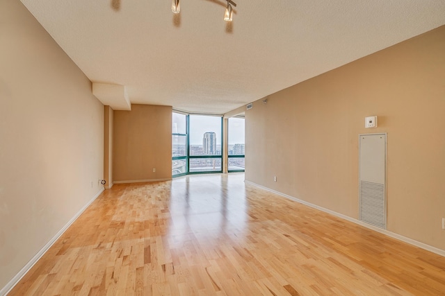 spare room with a textured ceiling, light hardwood / wood-style floors, and expansive windows