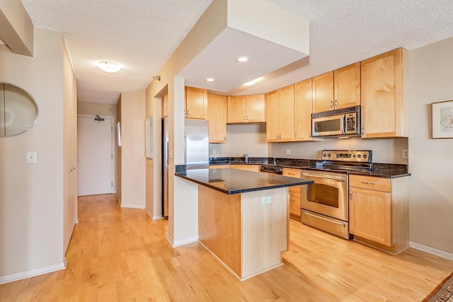 kitchen featuring a textured ceiling, a kitchen island, stainless steel appliances, light hardwood / wood-style floors, and sink