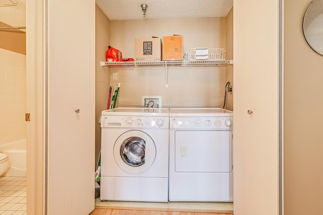 clothes washing area with independent washer and dryer and a textured ceiling