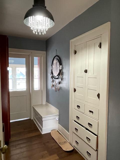 mudroom featuring dark wood-type flooring and an inviting chandelier