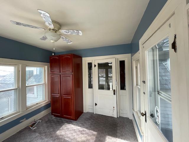 unfurnished bedroom with ceiling fan and dark colored carpet