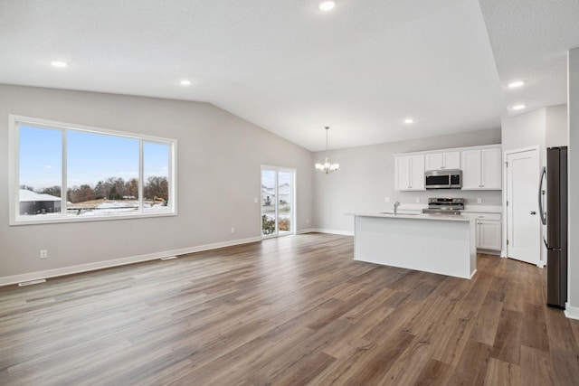 kitchen featuring stainless steel appliances, wood-type flooring, decorative light fixtures, a center island with sink, and white cabinets