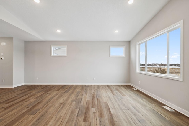 unfurnished room with plenty of natural light, light wood-type flooring, and vaulted ceiling