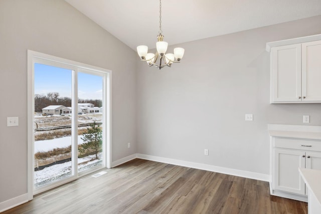 unfurnished dining area with lofted ceiling, light wood-type flooring, and an inviting chandelier