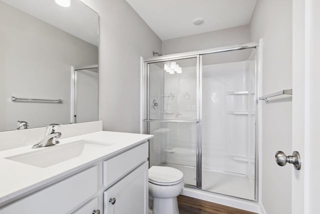 bathroom featuring wood-type flooring, vanity, toilet, and an enclosed shower