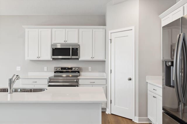 kitchen with white cabinets, wood-type flooring, stainless steel appliances, and sink