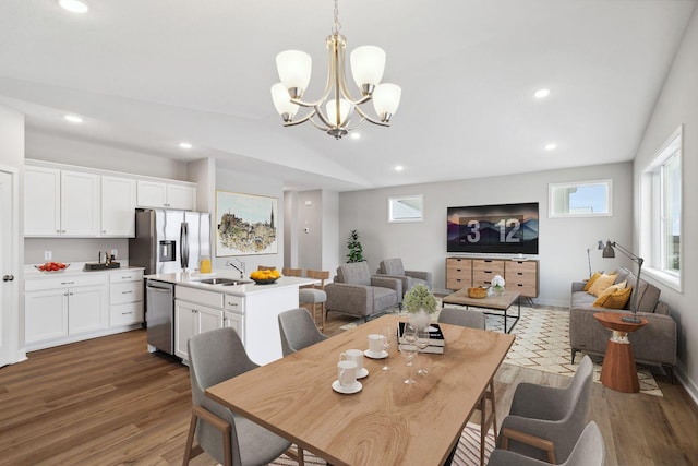 dining space with dark hardwood / wood-style flooring, an inviting chandelier, vaulted ceiling, and sink