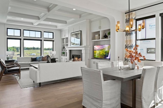 dining room featuring beam ceiling, built in shelves, coffered ceiling, light hardwood / wood-style flooring, and a chandelier