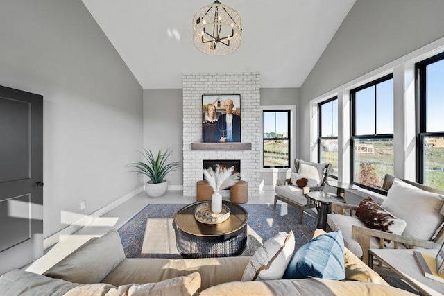 living room with high vaulted ceiling, an inviting chandelier, a healthy amount of sunlight, and a brick fireplace