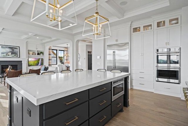 kitchen featuring built in appliances, white cabinets, hanging light fixtures, and a kitchen island