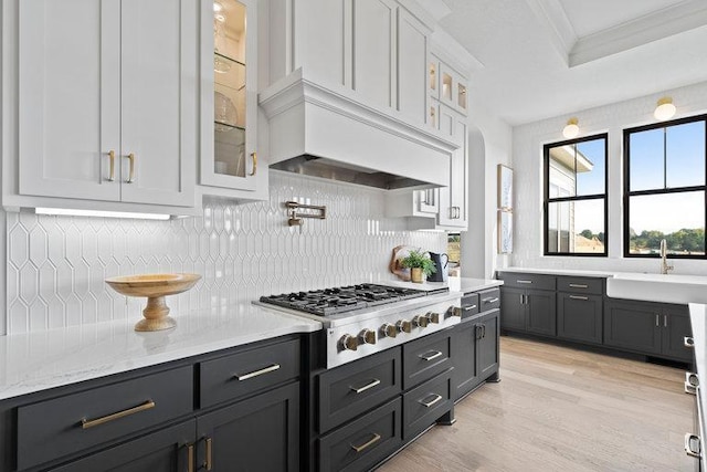 kitchen featuring stainless steel gas stovetop, custom exhaust hood, backsplash, white cabinets, and sink