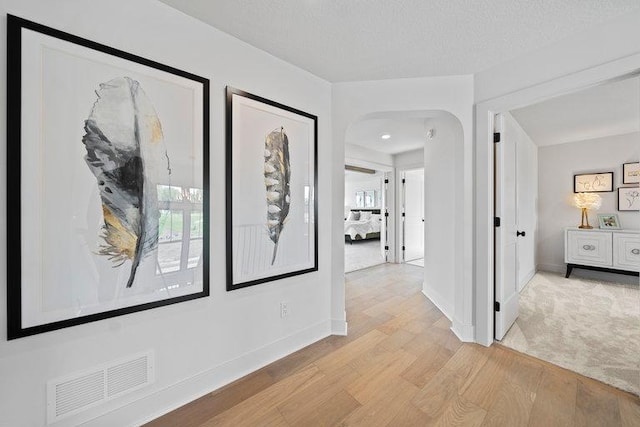 corridor featuring a textured ceiling and light wood-type flooring