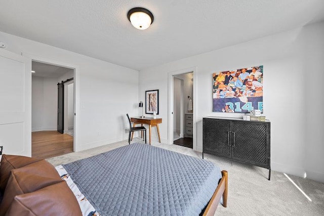 carpeted bedroom featuring connected bathroom and a barn door