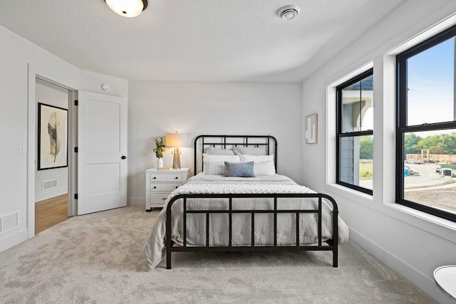 bedroom with a textured ceiling and light carpet