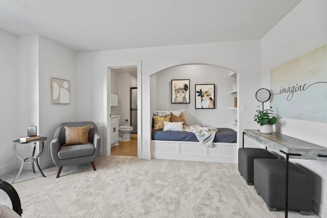 carpeted bedroom featuring a textured ceiling and connected bathroom