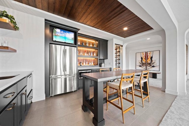 kitchen with built in features, stainless steel appliances, dark tile patterned flooring, and wood ceiling