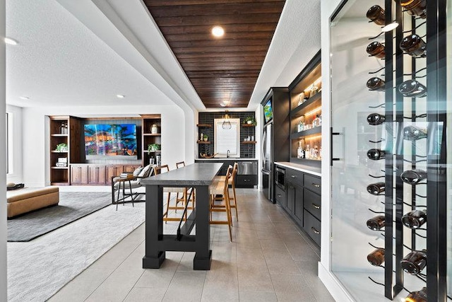 dining area featuring built in shelves, sink, a textured ceiling, light tile patterned flooring, and wood ceiling