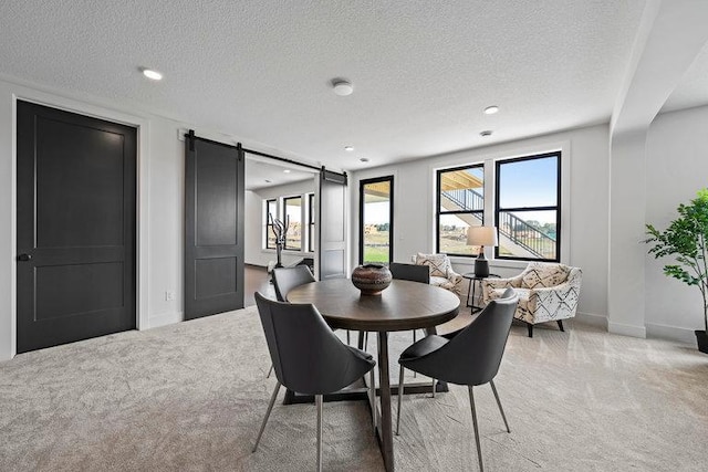 dining room with carpet flooring, a barn door, and a textured ceiling