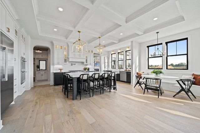 kitchen with arched walkways, breakfast area, a breakfast bar, beamed ceiling, and light countertops