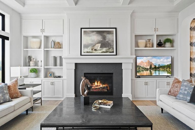 living room with light wood-style flooring, built in features, beam ceiling, and a high end fireplace