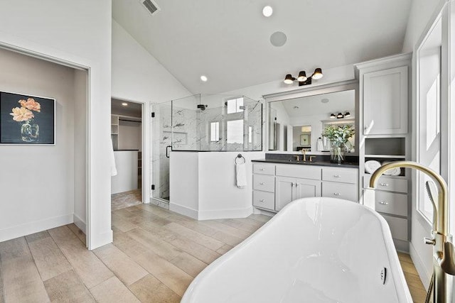 bathroom with visible vents, lofted ceiling, wood finished floors, vanity, and a shower stall