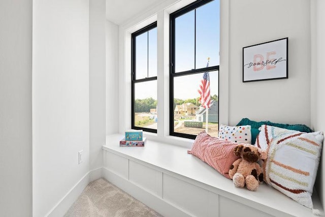 living area featuring light carpet and baseboards