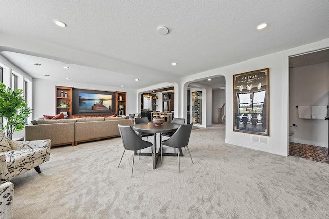 dining room with arched walkways, light colored carpet, a textured ceiling, and recessed lighting