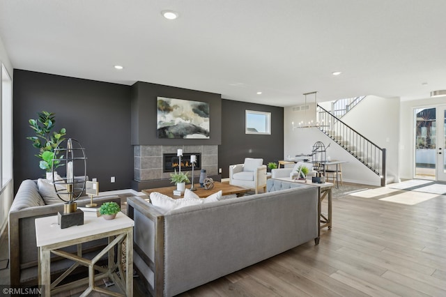 living room with a tiled fireplace and light wood-type flooring