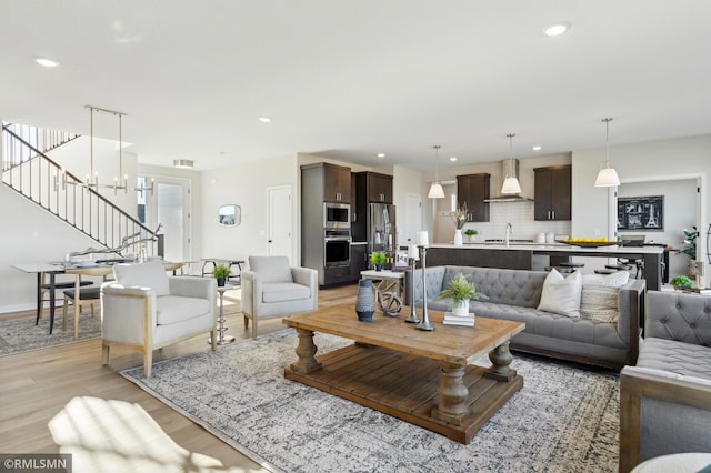 living room with sink, light hardwood / wood-style flooring, and a notable chandelier