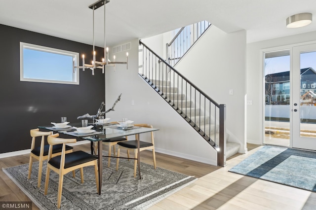 dining room with plenty of natural light, wood-type flooring, and a notable chandelier