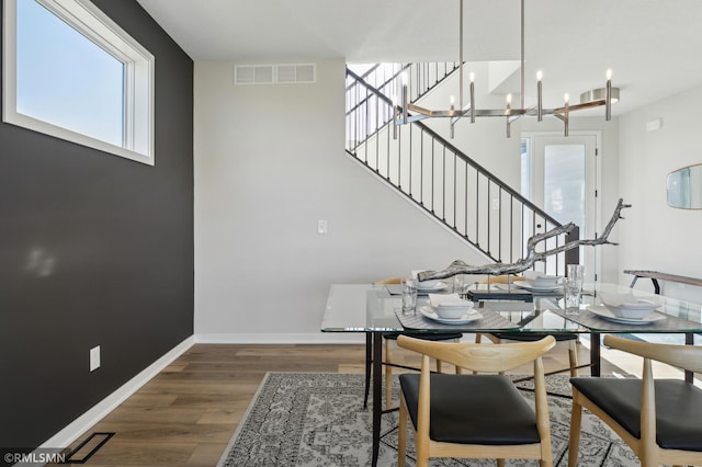 dining area with dark wood-type flooring and a notable chandelier