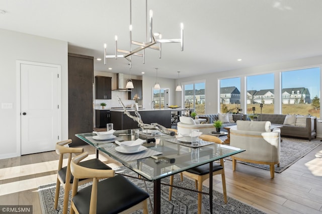 dining space with light wood-type flooring and an inviting chandelier