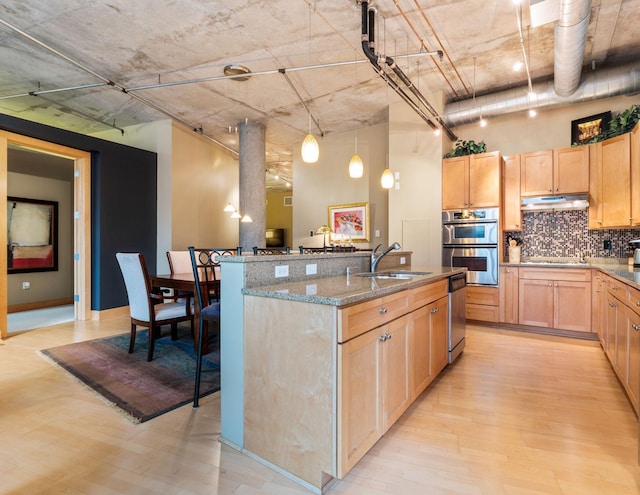 kitchen with light stone counters, backsplash, light wood-type flooring, light brown cabinetry, and appliances with stainless steel finishes