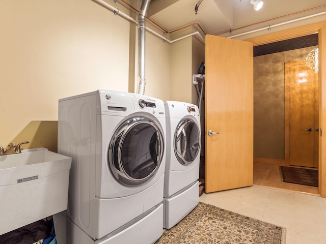 clothes washing area with independent washer and dryer and sink