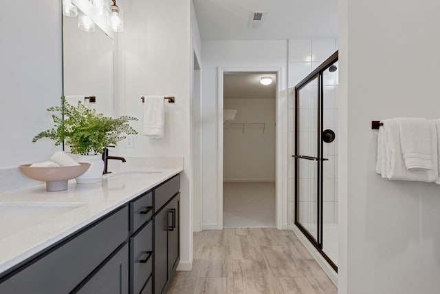 bathroom with a shower with shower door, hardwood / wood-style floors, and vanity