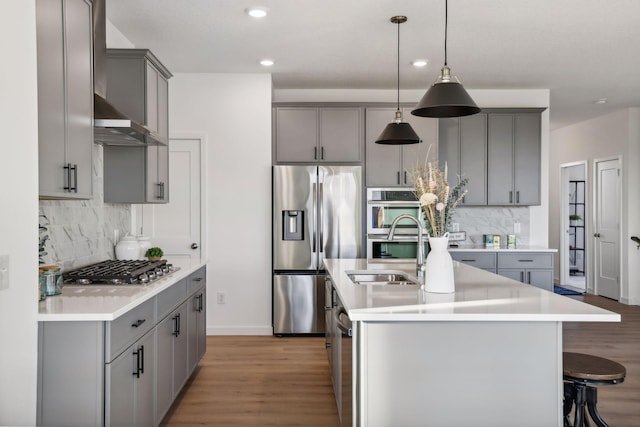 kitchen featuring stainless steel appliances, a kitchen island with sink, gray cabinetry, and sink